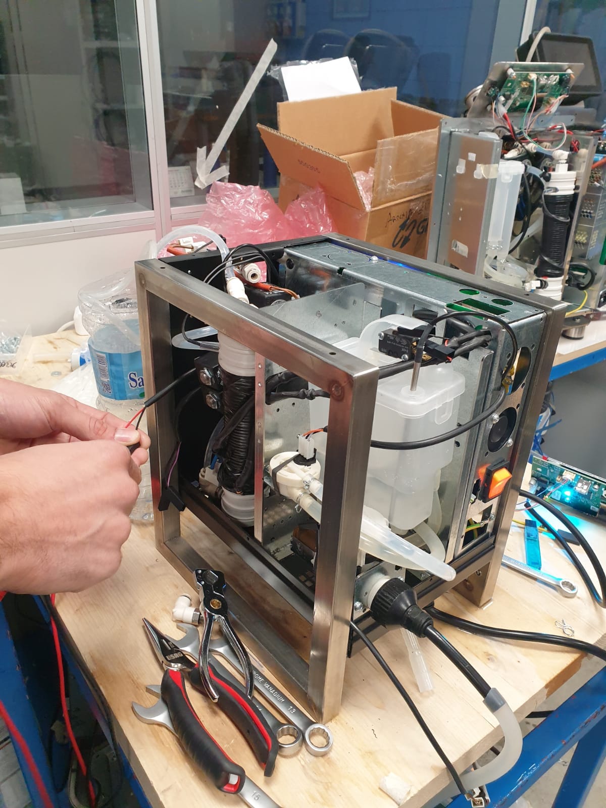Frühes Heylo Prototypen-Chassis auf einer Werkbank, Pumpe, Schläuche und Verkabelung offen, ein Techniker justiert ein Kabel