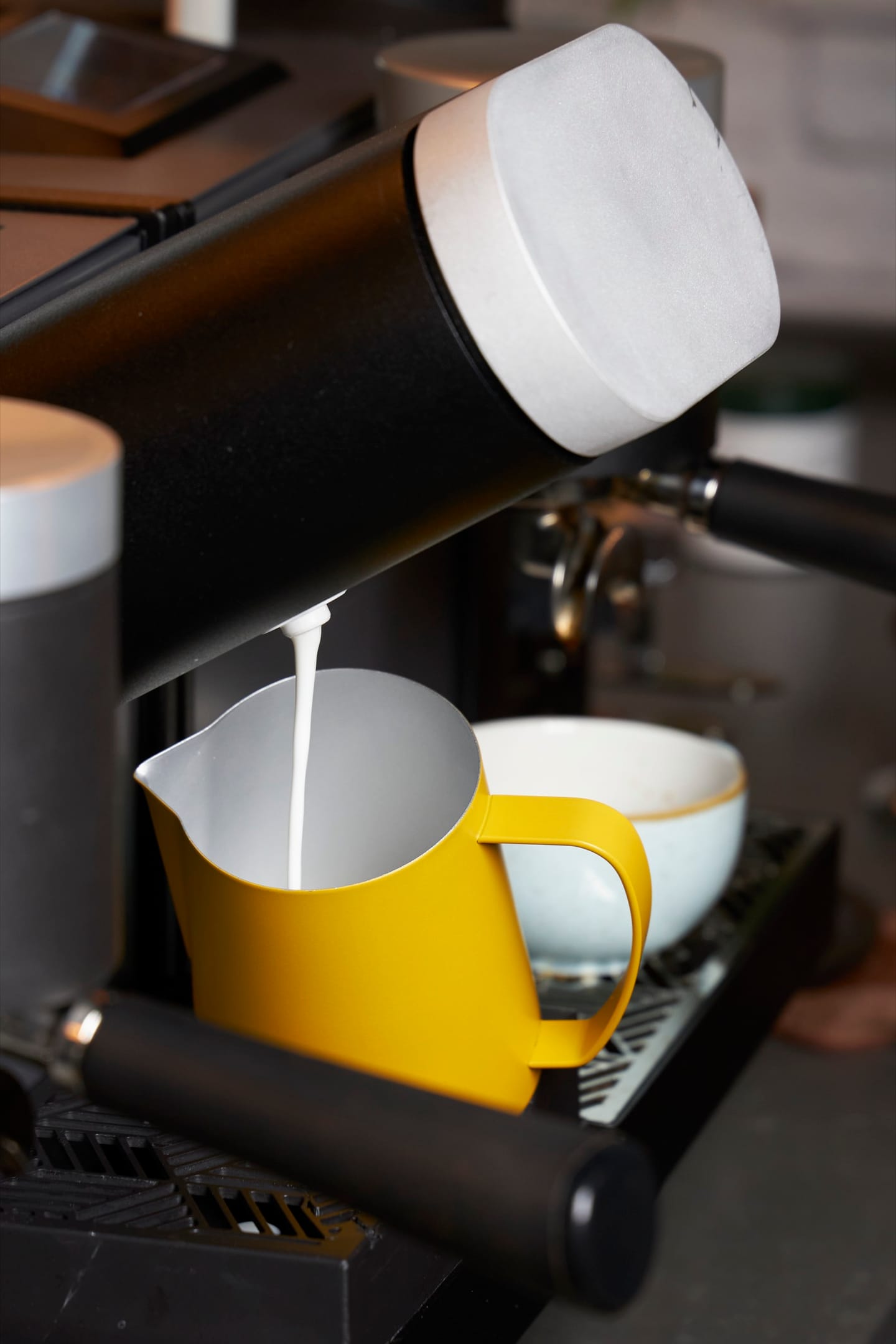 Heylo Milk Unit che versa latte texturizzato in una lattiera, con la Heylo Coffee Unit accanto